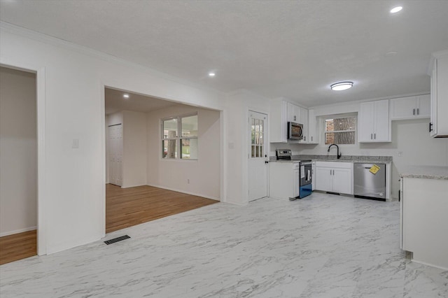 kitchen with white cabinets, sink, ornamental molding, and stainless steel appliances