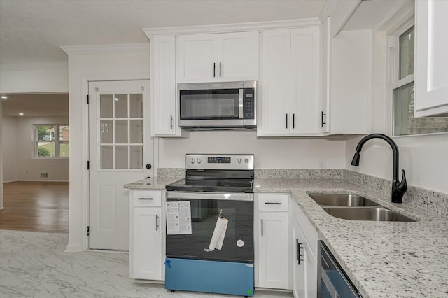 kitchen featuring light stone countertops, ornamental molding, stainless steel appliances, sink, and white cabinets