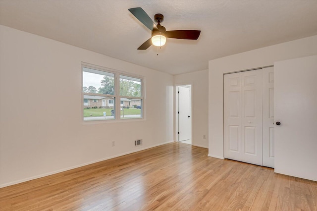 unfurnished bedroom with ceiling fan, a closet, and light wood-type flooring