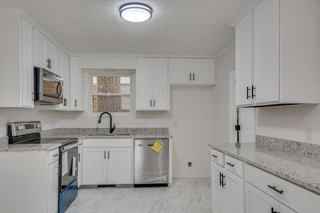 kitchen featuring white cabinetry, sink, stainless steel appliances, light stone counters, and a textured ceiling