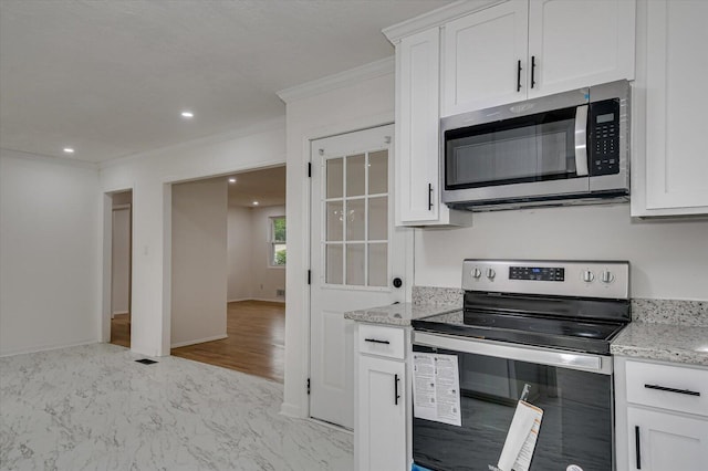 kitchen featuring white cabinetry, ornamental molding, light stone counters, and appliances with stainless steel finishes