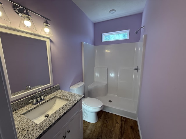 bathroom featuring wood-type flooring, vanity, toilet, and walk in shower