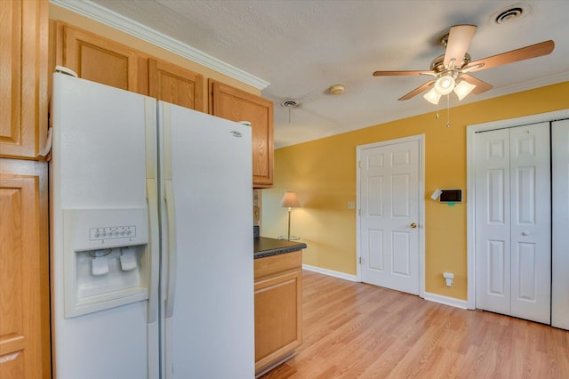 kitchen featuring dark countertops, light wood-style flooring, ceiling fan, crown molding, and white fridge with ice dispenser