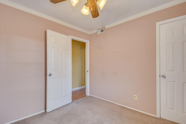 unfurnished bedroom with visible vents, crown molding, light carpet, and baseboards