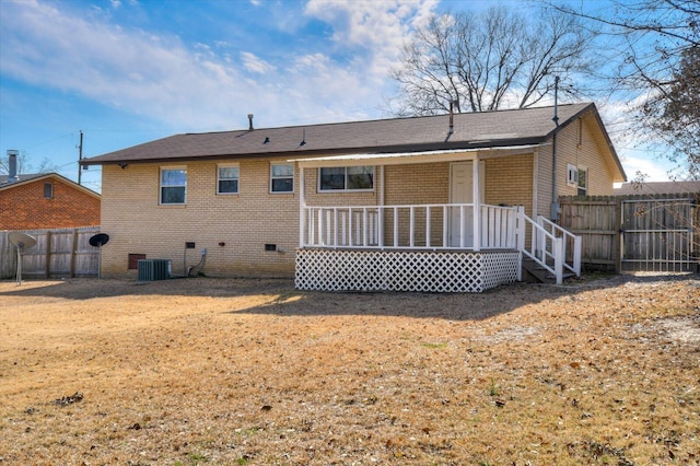 back of house featuring a porch, crawl space, brick siding, and fence