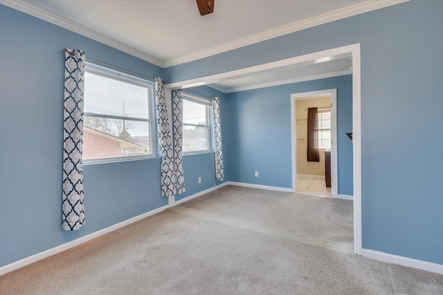 carpeted spare room featuring crown molding and baseboards