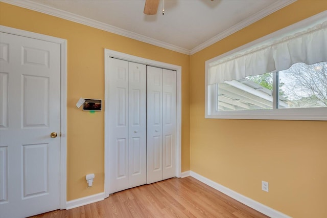 bedroom featuring light wood-style floors, a closet, baseboards, and crown molding