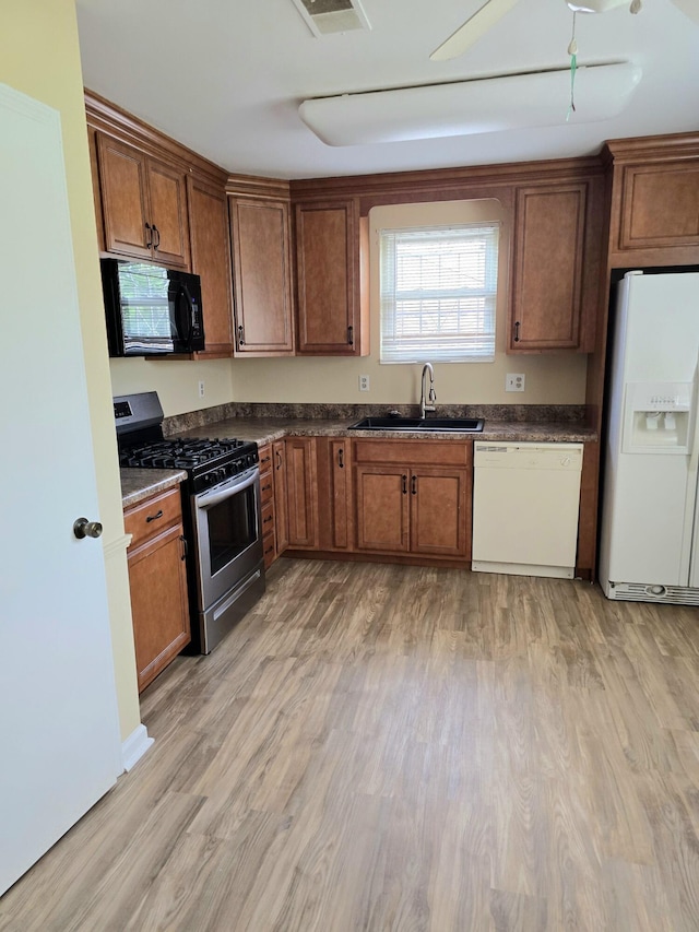 3807 Fairington Dr, Hephzibah, GA 30815 - kitchen with dark countertops, a sink, white appliances, baseboards, and light wood-style flooring