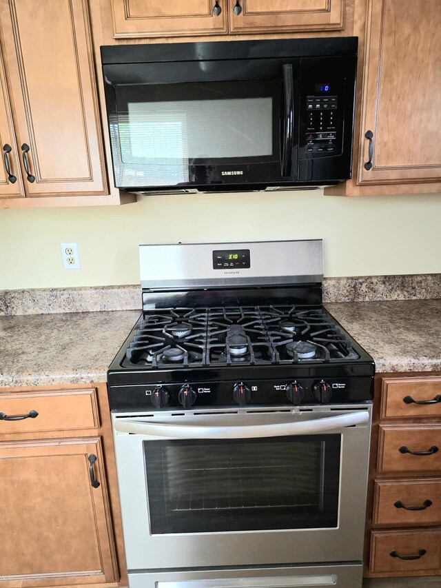3807 Fairington Dr, Hephzibah, GA 30815 - kitchen featuring light countertops, stainless steel range with gas cooktop, black microwave, and brown cabinetry