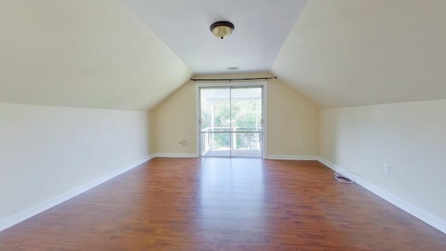 additional living space with dark wood-type flooring and vaulted ceiling