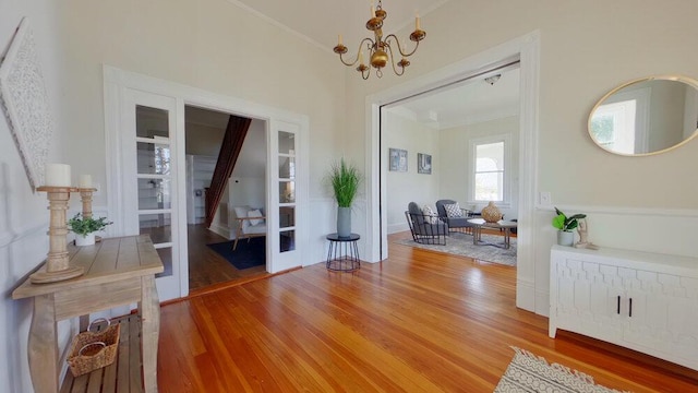 entryway with hardwood / wood-style flooring, crown molding, and a notable chandelier