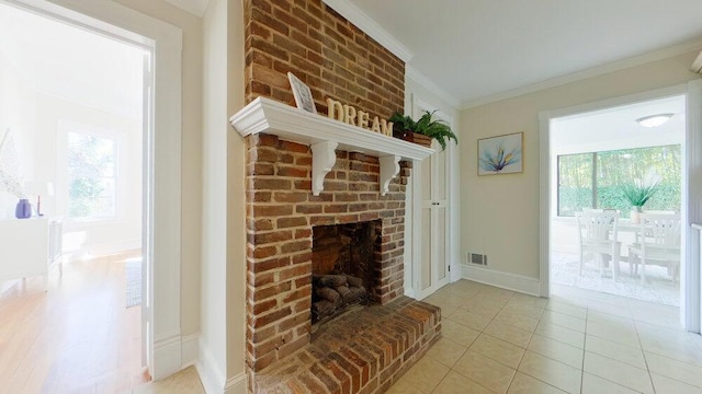 unfurnished living room featuring crown molding, a brick fireplace, and light tile patterned floors