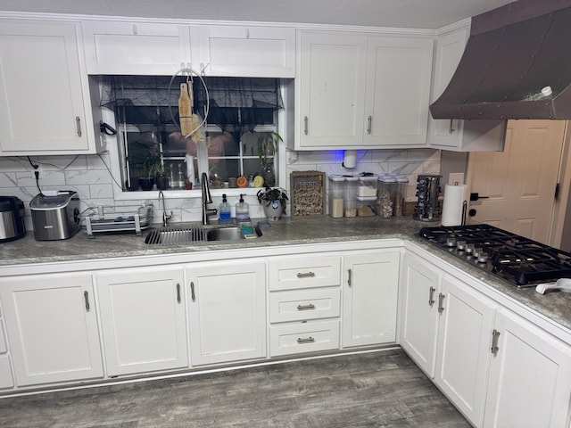 kitchen featuring stainless steel gas stovetop, tasteful backsplash, sink, white cabinets, and wall chimney exhaust hood