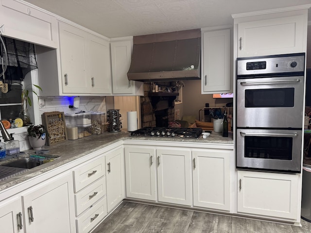 kitchen featuring white cabinetry, stainless steel appliances, and wall chimney range hood