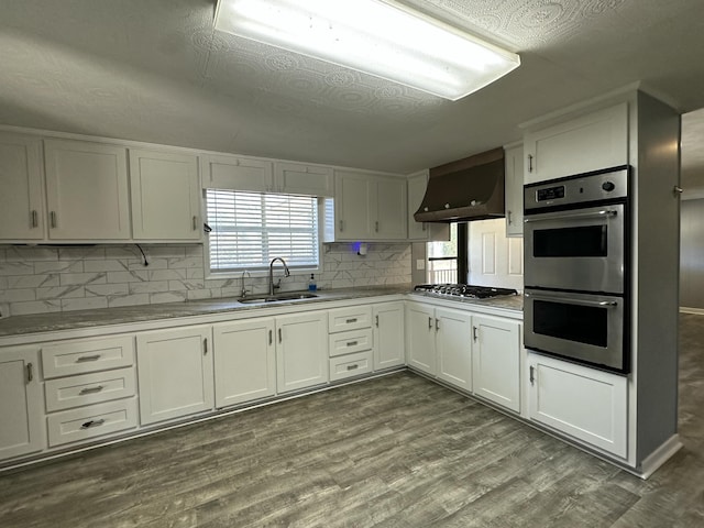 kitchen with white cabinetry, appliances with stainless steel finishes, extractor fan, and a sink