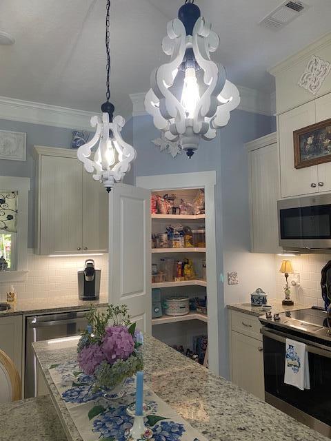 256 Candlewick Loop, Mccormick, SC 29835 - kitchen featuring appliances with stainless steel finishes, a chandelier, backsplash, light stone countertops, and crown molding
