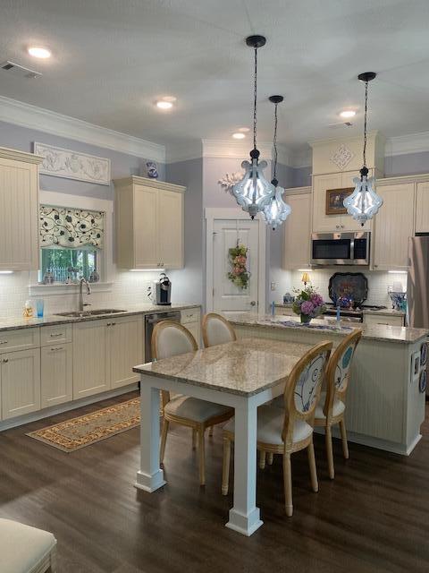256 Candlewick Loop, Mccormick, SC 29835 - kitchen with stainless steel appliances, a kitchen bar, backsplash, ornamental molding, and decorative light fixtures