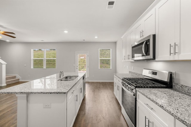 kitchen with stainless steel appliances, sink, a center island with sink, and white cabinets