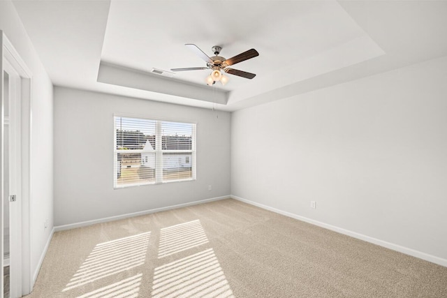 unfurnished room featuring light carpet, a raised ceiling, and ceiling fan