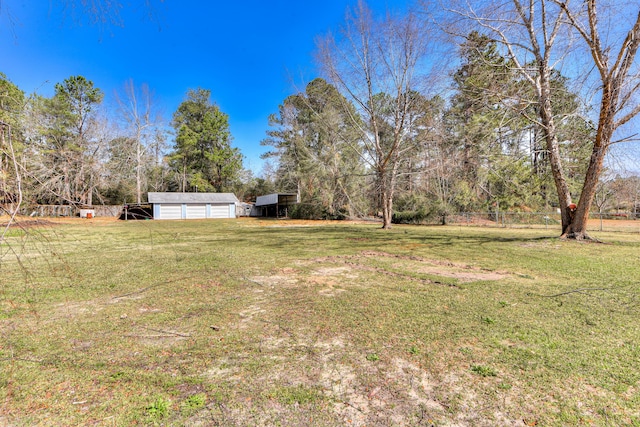 view of yard with an outbuilding, a detached garage, and fence