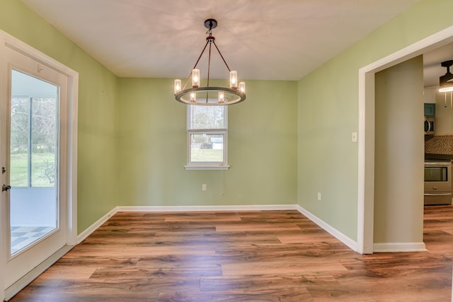 unfurnished room featuring wood finished floors, a wealth of natural light, and baseboards