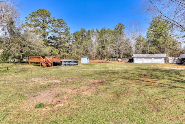 view of yard featuring a deck, a storage unit, an outdoor structure, and a detached garage