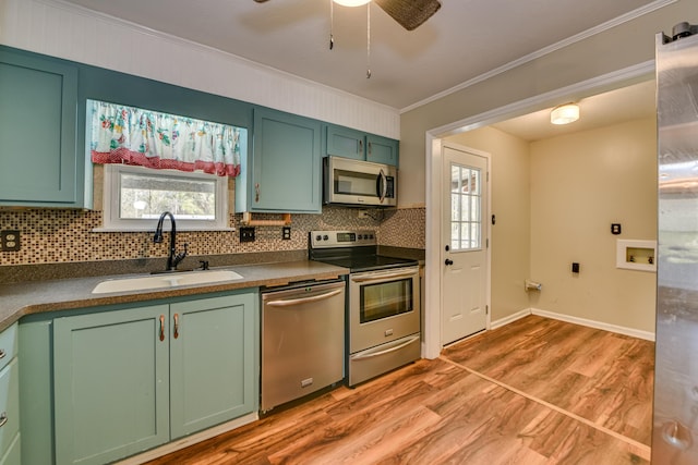 kitchen with stainless steel appliances, light wood-style floors, green cabinetry, and a sink