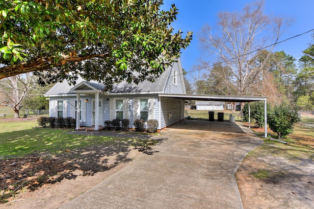 view of front facade featuring a carport, roof with shingles, a front yard, and driveway