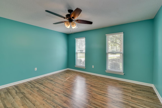 spare room featuring a ceiling fan, a textured ceiling, baseboards, and wood finished floors