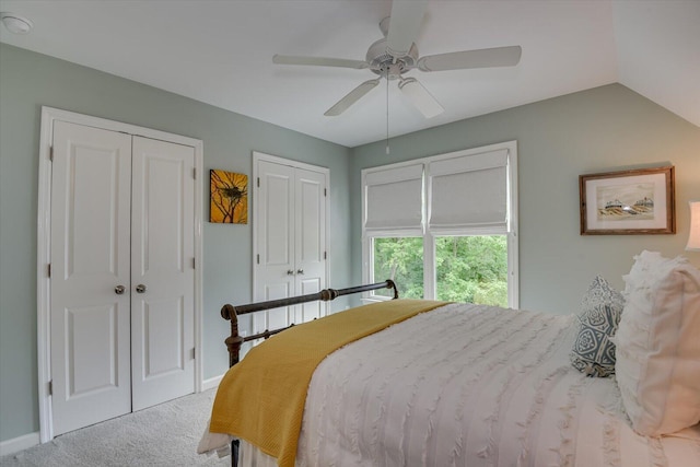 carpeted bedroom with ceiling fan, lofted ceiling, and two closets