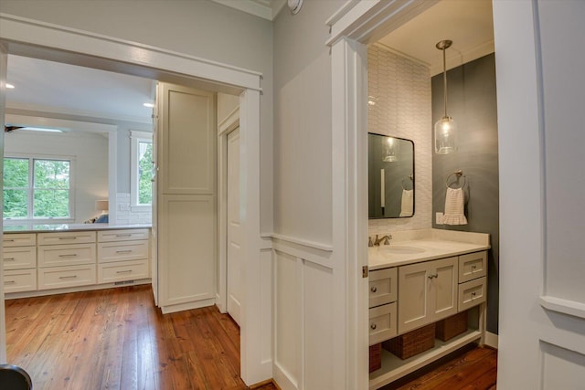 bathroom with decorative backsplash, hardwood / wood-style floors, vanity, and ornamental molding