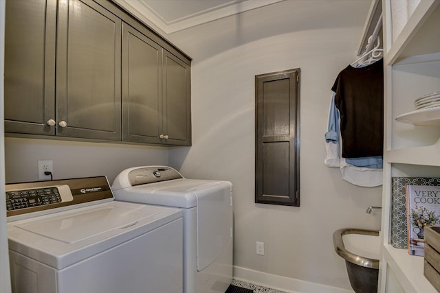 clothes washing area featuring washer and dryer, ornamental molding, and cabinets