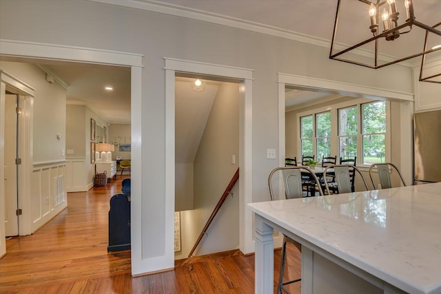 dining space with light hardwood / wood-style flooring, ornamental molding, and an inviting chandelier