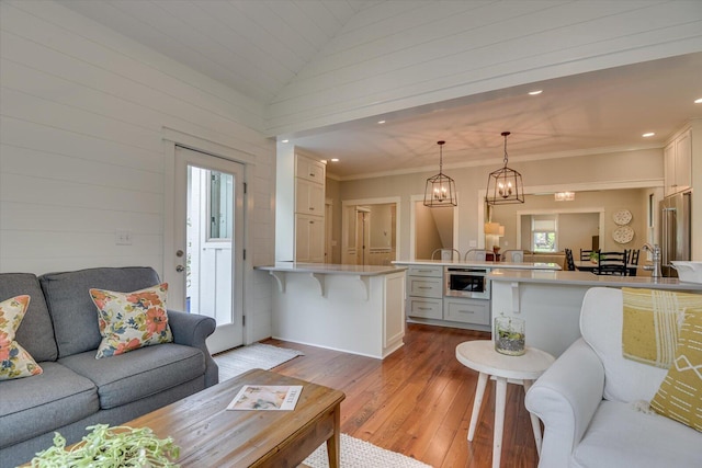 living room with light hardwood / wood-style floors, vaulted ceiling, and a notable chandelier