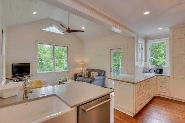 kitchen with light wood-type flooring, stainless steel dishwasher, ceiling fan, sink, and lofted ceiling