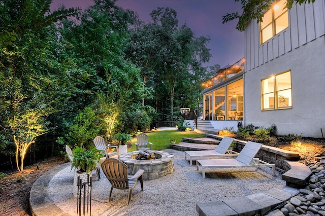 patio terrace at dusk featuring a fire pit and a sunroom