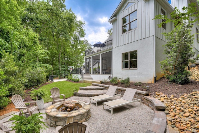 view of patio with an outdoor fire pit and a sunroom