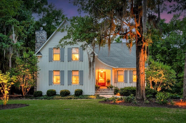 back house at dusk with a lawn