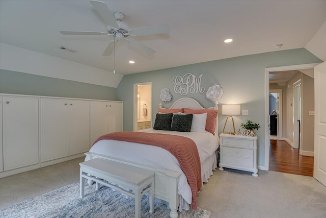 bedroom featuring connected bathroom, light colored carpet, vaulted ceiling, and ceiling fan