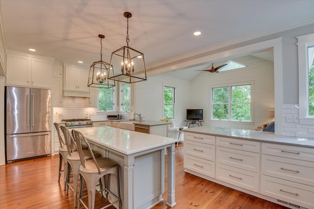 kitchen featuring white cabinets, decorative light fixtures, a center island, and appliances with stainless steel finishes