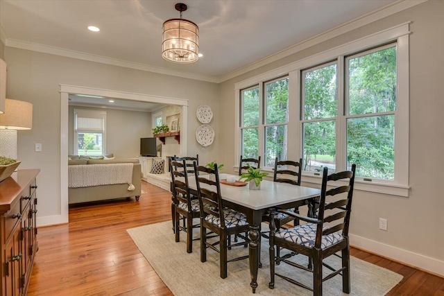 dining room with a wealth of natural light, light hardwood / wood-style flooring, crown molding, and a notable chandelier