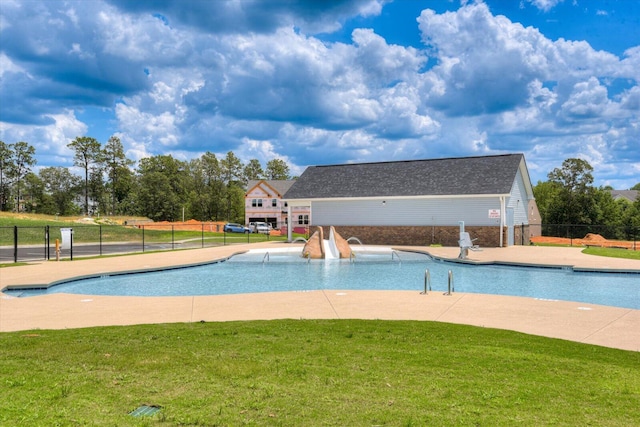 view of swimming pool with a lawn, a water slide, and a patio