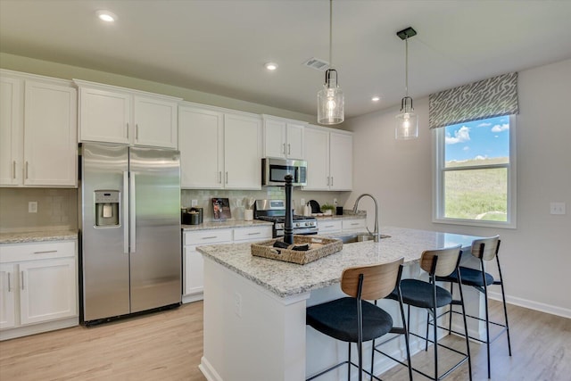 kitchen featuring tasteful backsplash, white cabinetry, a center island with sink, and stainless steel appliances