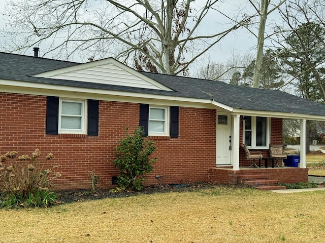 single story home with roof with shingles, brick siding, a front lawn, and a porch