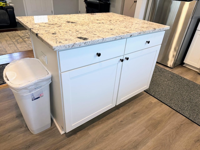 kitchen with dark wood-style floors, light stone counters, white cabinets, and a center island