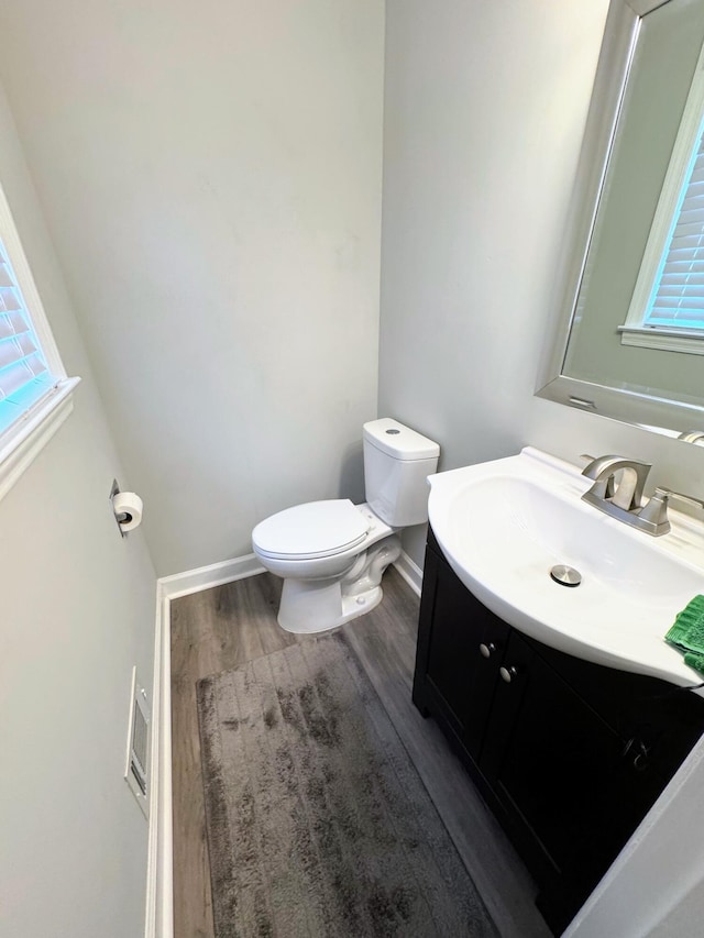 bathroom with toilet, baseboards, wood finished floors, and vanity