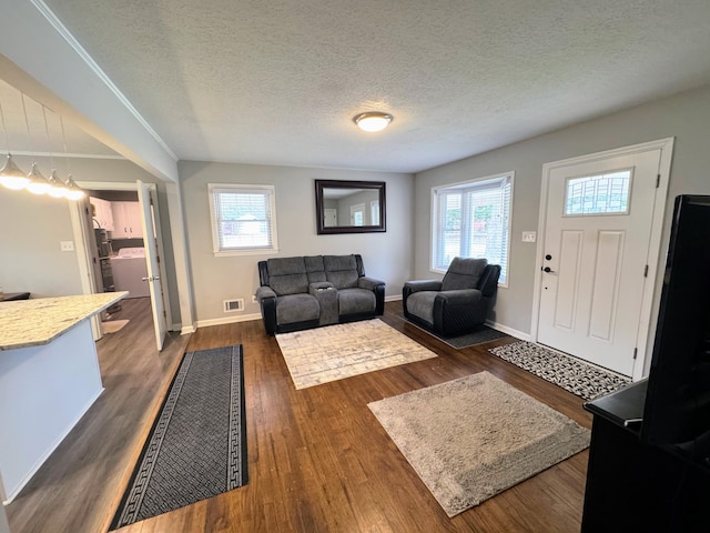 living room featuring baseboards, visible vents, dark wood finished floors, and a textured ceiling