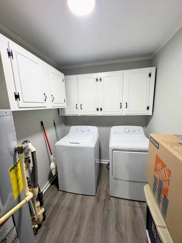 laundry room featuring washing machine and clothes dryer, cabinet space, dark wood-type flooring, ornamental molding, and baseboards