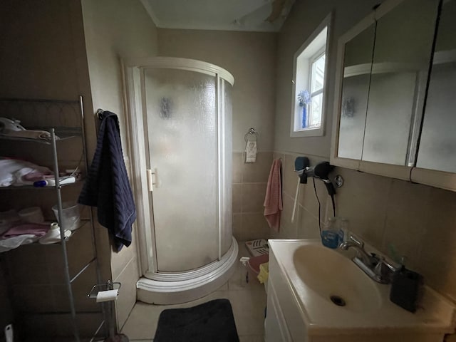 bathroom featuring vanity, tile patterned floors, a shower with door, and tile walls