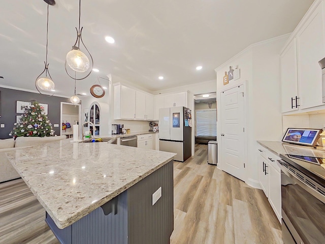 kitchen with sink, hanging light fixtures, a large island with sink, white cabinets, and appliances with stainless steel finishes